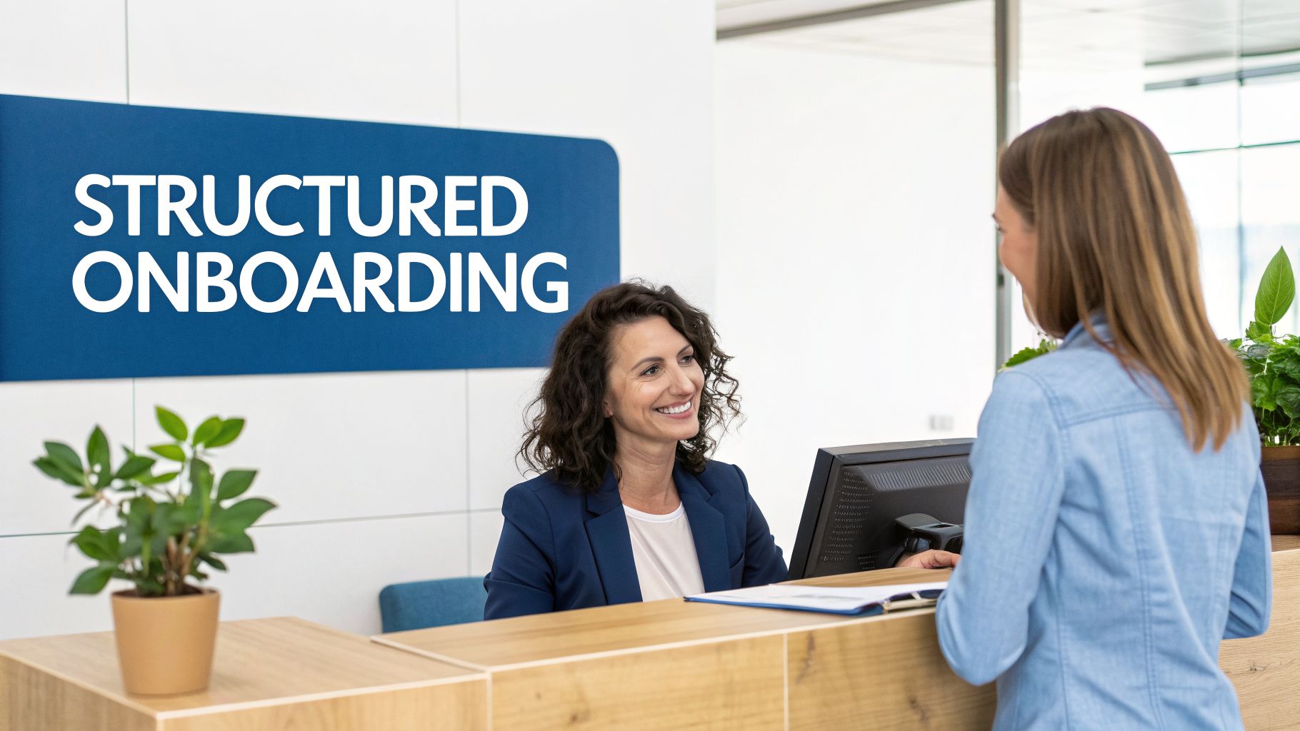 A friendly employee smiling at a new hire at a reception desk with a 'STRUCTURED ONBOARDING' sign.