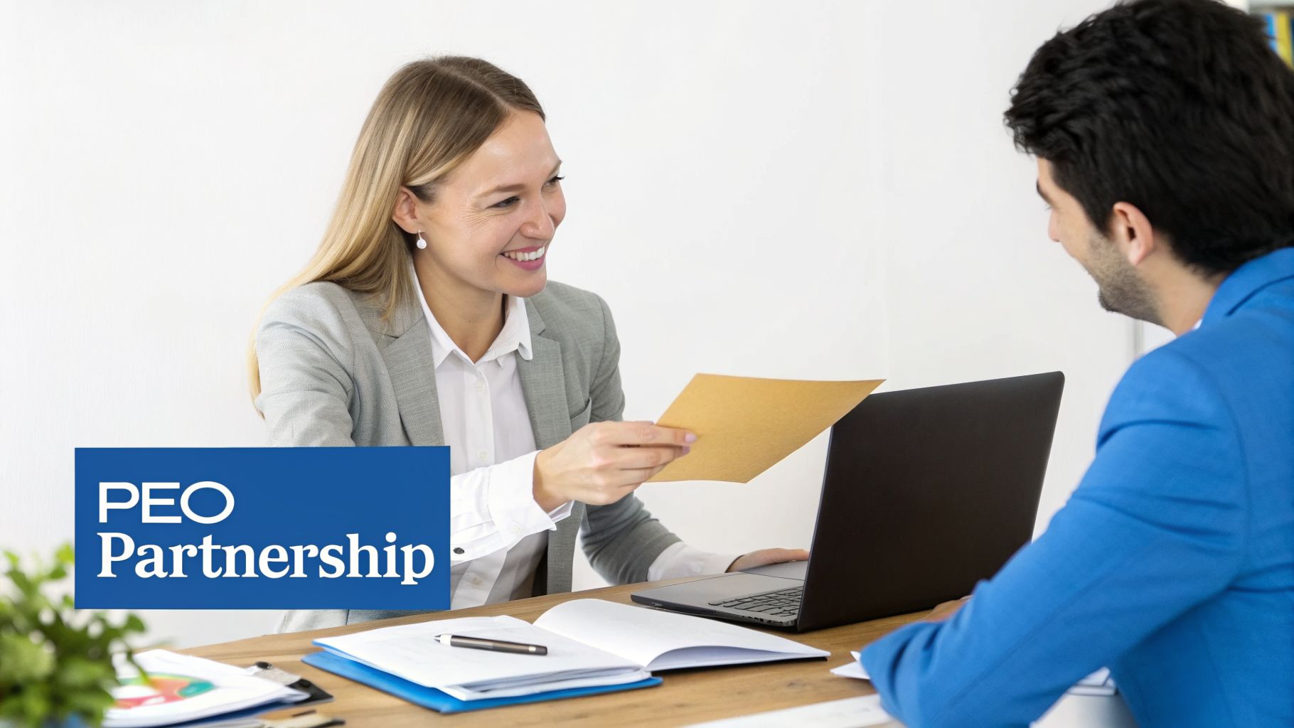 A businesswoman smiling while passing a document to a male colleague or client at a desk.